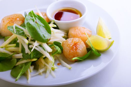 Scallop salad with apple, spinach on a stone plate