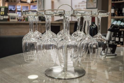 close up empty wine glasses hanging upside down in a wine store. France