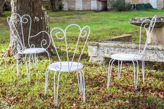 Decorative vintage metal white chairs furniture in a garden in France