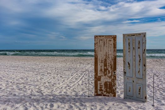 A conceptual design with doors on the sand in front of the surf.