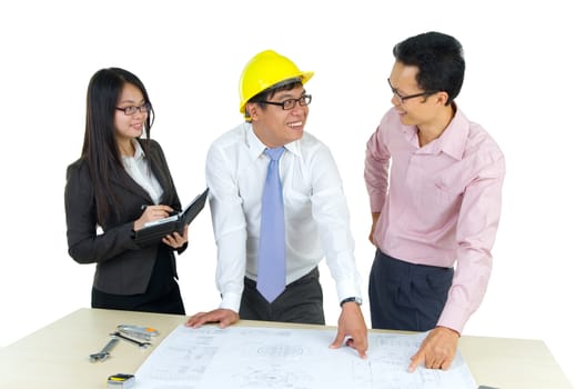 Three architects standing in front of table and having discussing on the paperwork.