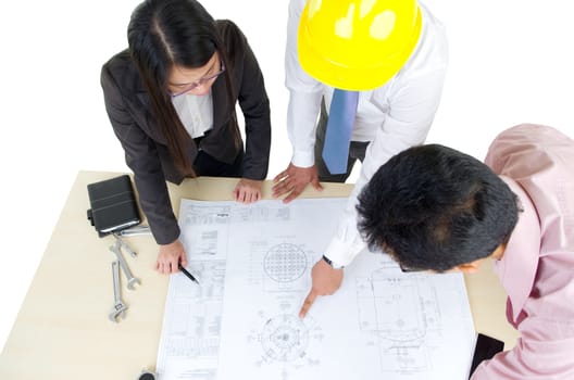Above view of three architects standing in front of the table and discussing design project.