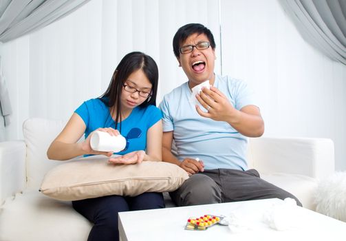 Asian man having medicine at home. Wife take care of her husband.