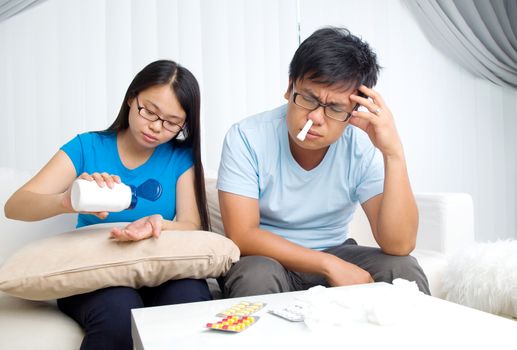 Asian man having medicine at home. Wife take care of her husband.