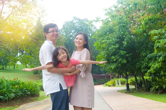 Portrait of joyful happy Asian family playing together at outdoor park during summer sunset.