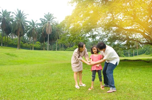 Portrait of joyful happy Asian family playing together at outdoor park during summer sunset.