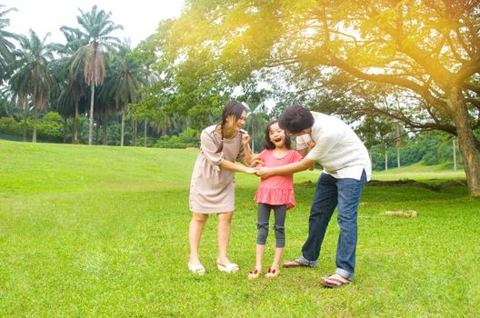 Portrait of joyful happy Asian family playing together at outdoor park during summer sunset.