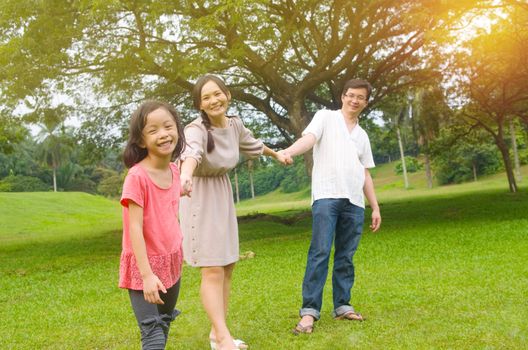 Portrait of joyful happy Asian family playing together at outdoor park during summer sunset.