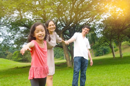 Portrait of joyful happy Asian family playing together at outdoor park during summer sunset.