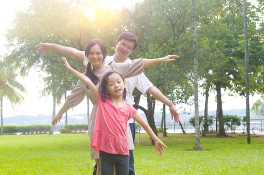 Portrait of joyful happy Asian family playing together at outdoor park during summer sunset.