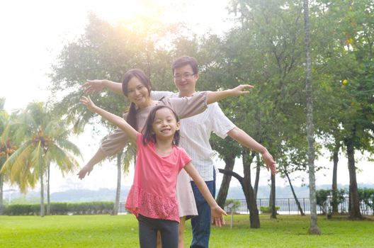 Portrait of joyful happy Asian family playing together at outdoor park during summer sunset.