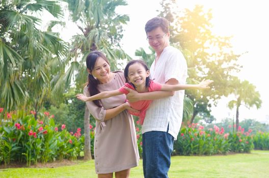 Portrait of joyful happy Asian family playing together at outdoor park during summer sunset.