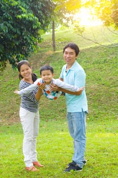 Portrait of joyful happy Asian family playing together at outdoor park during summer sunset.