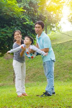 Portrait of joyful happy Asian family playing together at outdoor park during summer sunset.