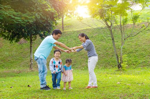 Asian family outdoor quality time enjoyment, asian people playing during beautiful sunset.