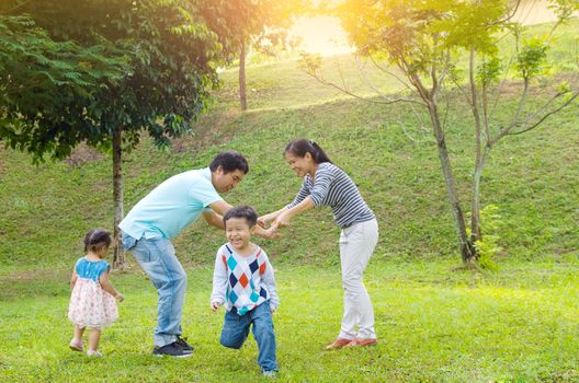 Asian family outdoor quality time enjoyment, asian people playing during beautiful sunset.