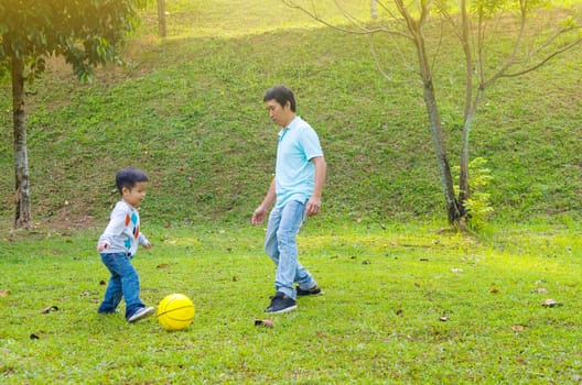 Asian father and son outdoor quality time enjoyment, asian people playing during beautiful sunset.