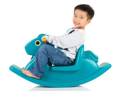 smiling asian boy playing with Toy horse