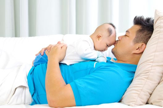 Asian father kissing his baby