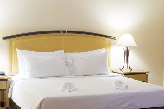 Big pillow on white and clean bed with lamp in bedroom at hotel.