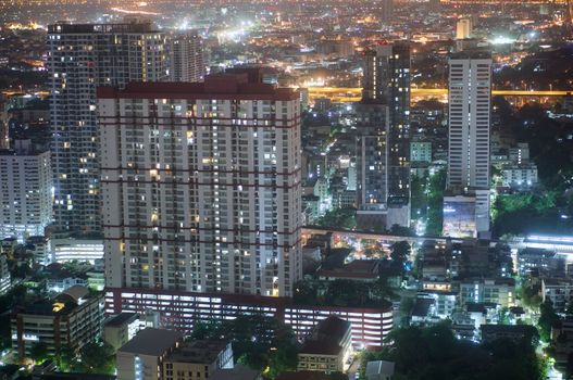 Condominium and skyscrapers on city scape at night in Bangkok Thailand.