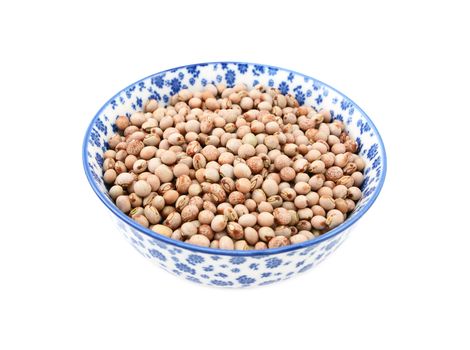 Pigeon peas in a blue and white porcelain bowl with a floral design, isolated on a white background
