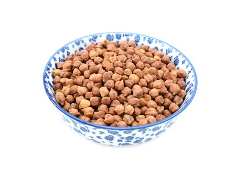 Black chickpeas in a blue and white porcelain bowl with a floral design, isolated on a white background
