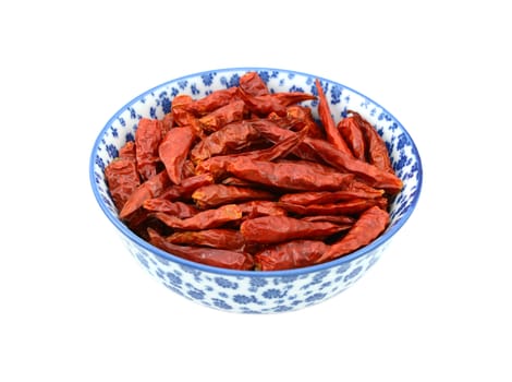 Birds eye chillis in a blue and white porcelain bowl with a floral design, isolated on a white background