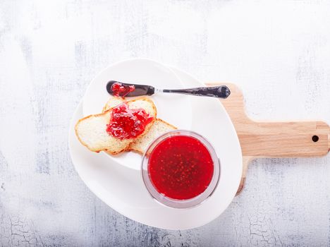 Raspberry jam in a glass bowl with toast