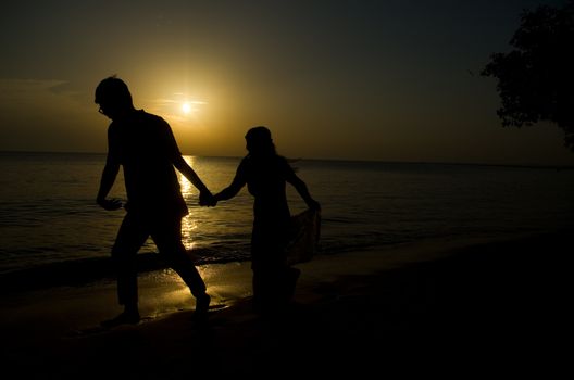 silhouette of a young bride and groom in beach on Sunset background