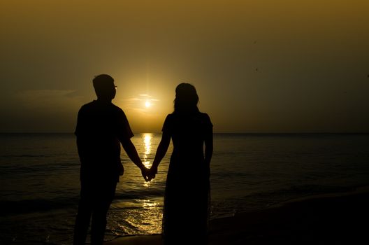 silhouette of a young bride and groom in beach on Sunset background