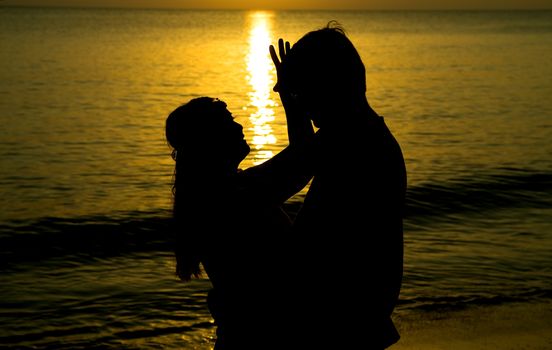 silhouette of a young bride and groom in beach on Sunset background