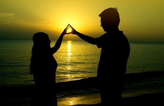 silhouette of a young bride and groom in beach on Sunset background