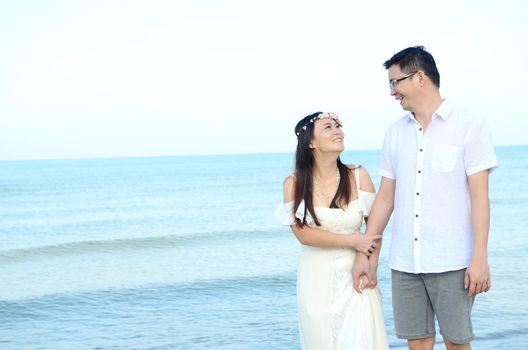 Asian bride and groom on a tropical beach. Wedding and honeymoon concept.