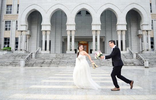 Happy bride and groom enjoying their wedding in the background of the building with beautiful architecture. Happy young wedding couple.