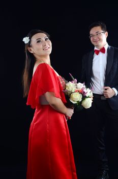 Portrait of young elegant enamoured just married groom and bride embracing at Wedding on black background