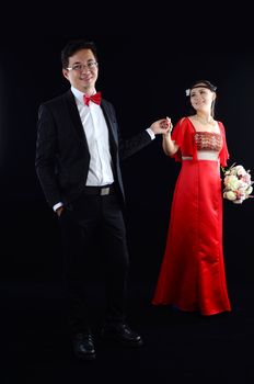 Portrait of young elegant enamoured just married groom and bride embracing at Wedding on black background