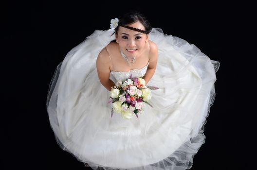 attractive asian woman wearing wedding dress isolated on black background