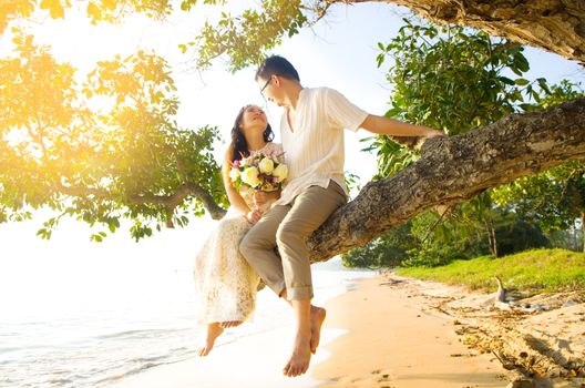 Outdoor Bride and groom on the beach with sunset in the evening.