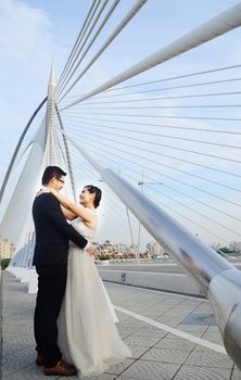 Happy bride and groom enjoying their wedding in the background of the bridge with beautiful architecture. Happy young wedding couple.