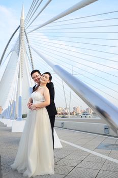 Happy bride and groom enjoying their wedding in the background of the bridge with beautiful architecture. Happy young wedding couple.