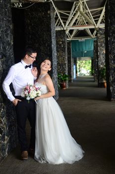 Happy bride and groom enjoying their wedding in the background of the building with beautiful architecture. Happy young wedding couple.