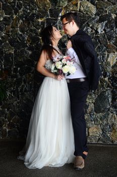 Happy bride and groom enjoying their wedding in the background of the building with beautiful architecture. Happy young wedding couple.