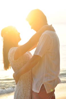 Outdoor Bride and groom on the beach with sunset in the evening.
