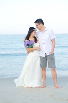 Asian bride and groom on a tropical beach. Wedding and honeymoon concept.