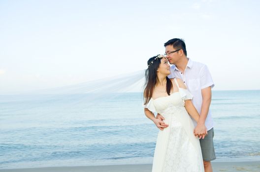 Asian bride and groom on a tropical beach. Wedding and honeymoon concept.