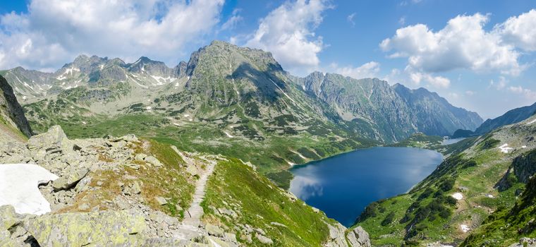 Panorama of the mountain valley with the craggy slopes and two lakes on the background of the sky with clouds
