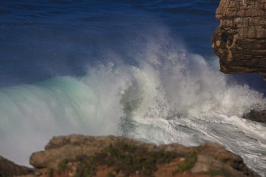 Marine wave breaks against offshore stone
