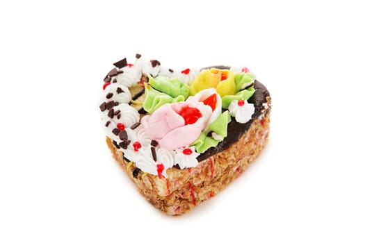 Chocolate cake in the shape of heart decorated with cream flowers isolated on white background. Confectionery, confection, pastry