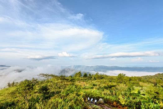 Tourists are walking on nature trails amidst the beautiful landscape of mountain range sky cloud and fog in the winter at Phu Chi Fa Forest Park, Chiang Rai Province, Thailand